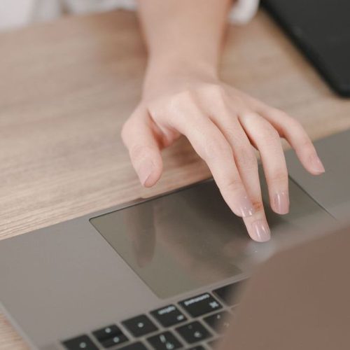 A woman is using a laptop on a wooden table